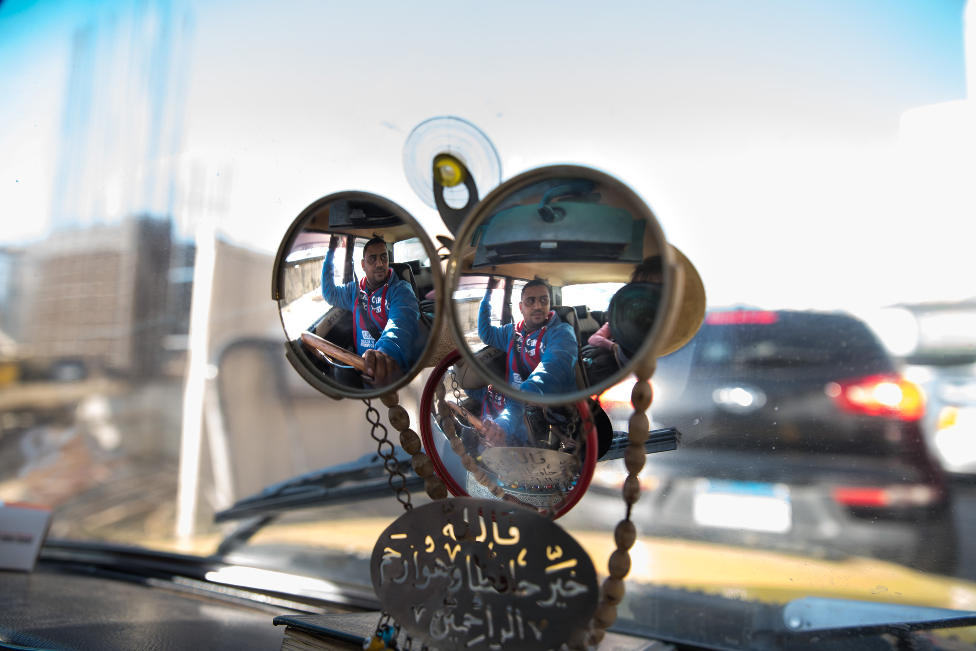A taxi driver is reflected in his car's mirrors while stuck in congestion.