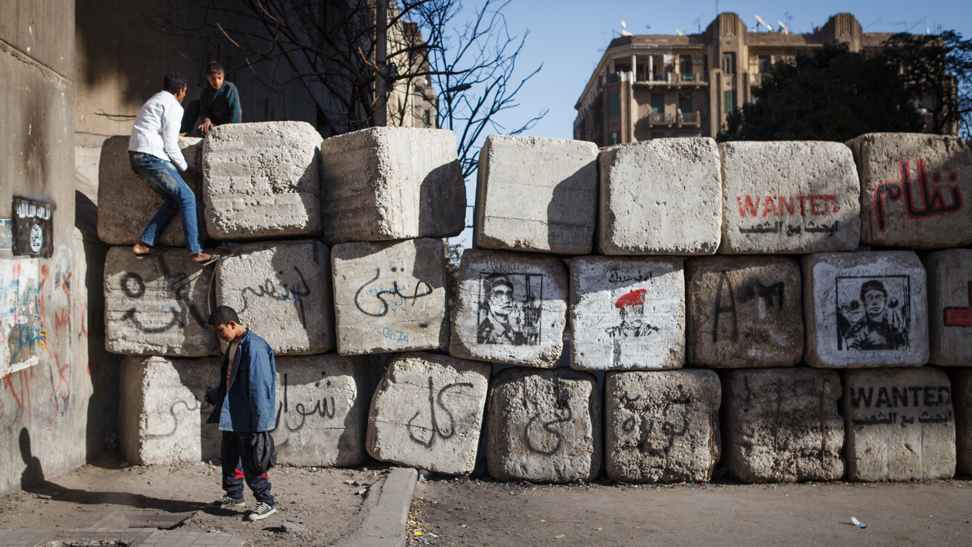 Youth clamber over a barrier in Cairo. 