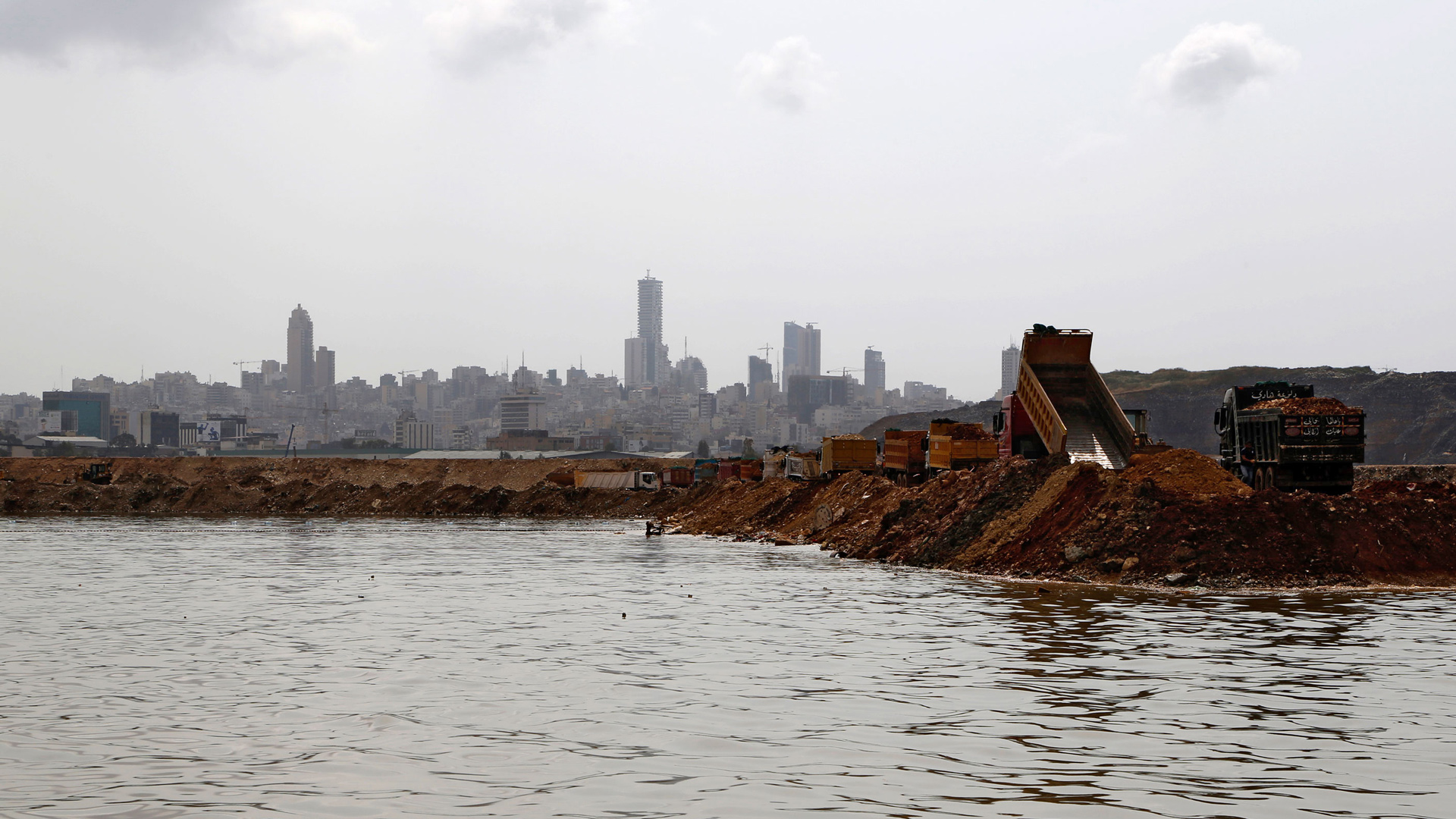 Trucks dump earth and trash into the sea as part of the land reclamation process at the Bourj Hammond landfill in Beirut. 