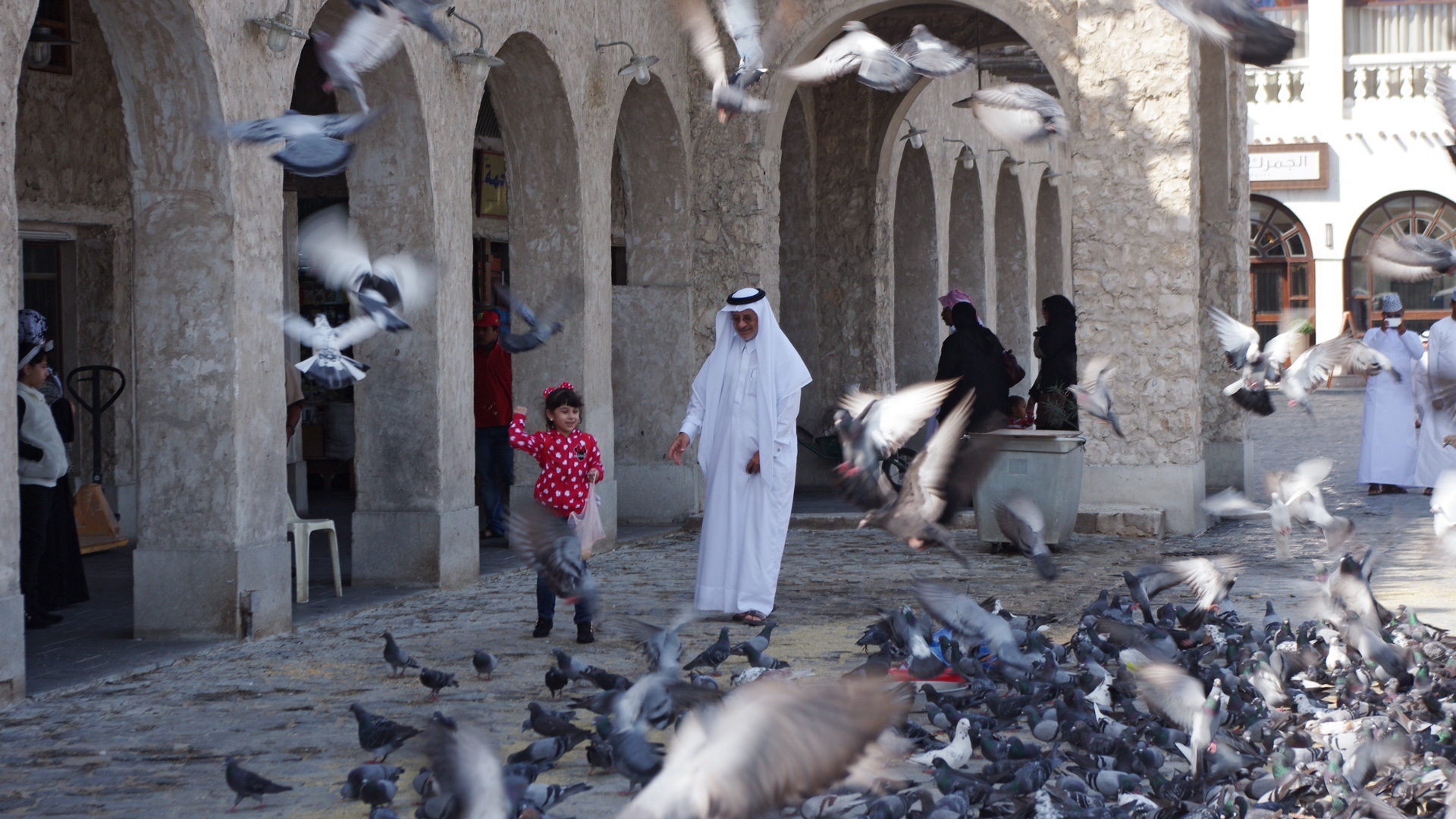 A man and girl feed pigeons in Doha, the capital of Qatar.
